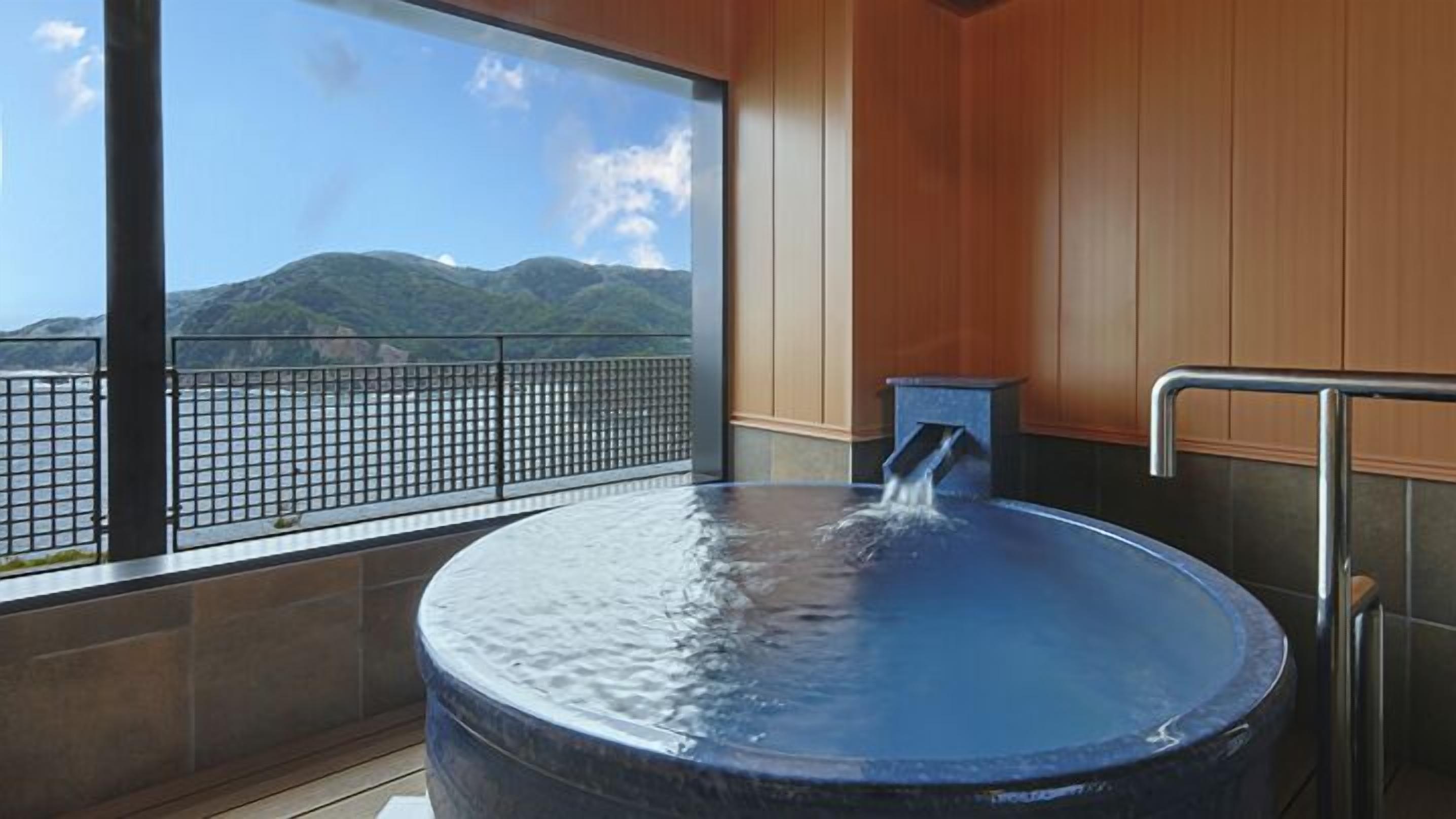 A hot tub with a view of mountains and a railing.