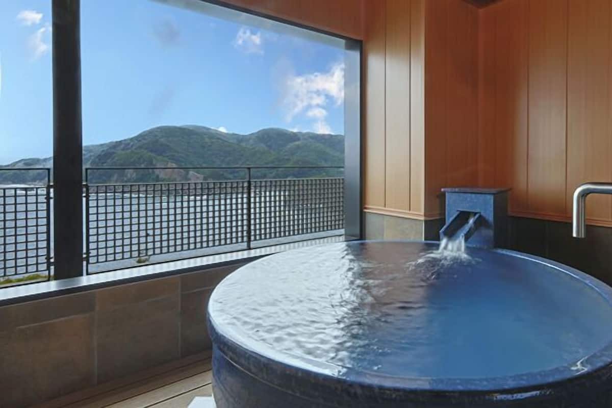 A hot tub with a view of mountains and a railing.