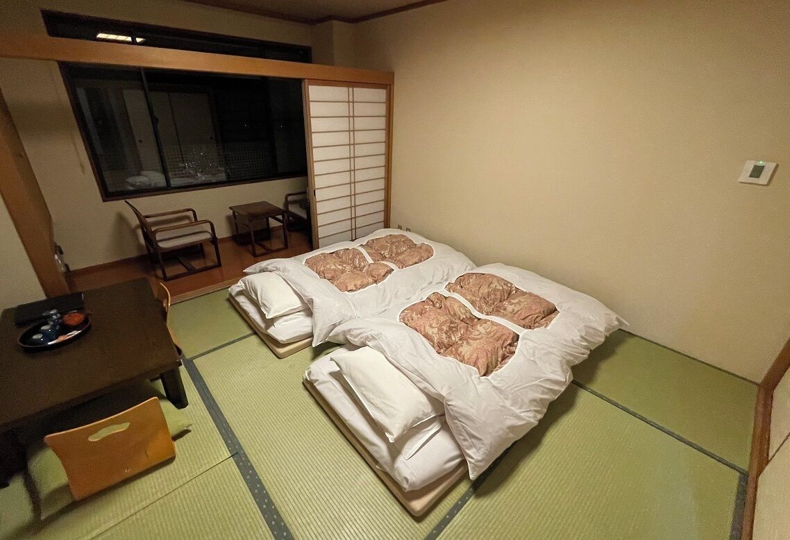 A room with two beds, a small table, and a chair.