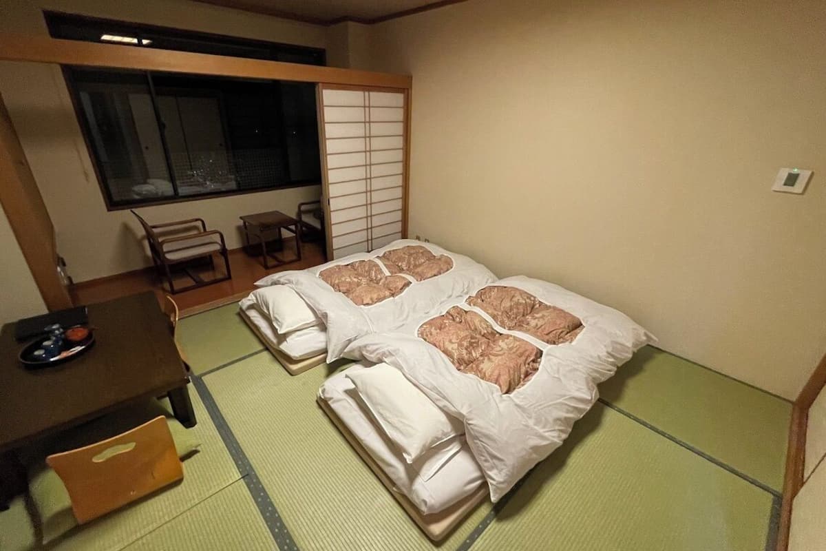 A room with two beds, a small table, and a chair.