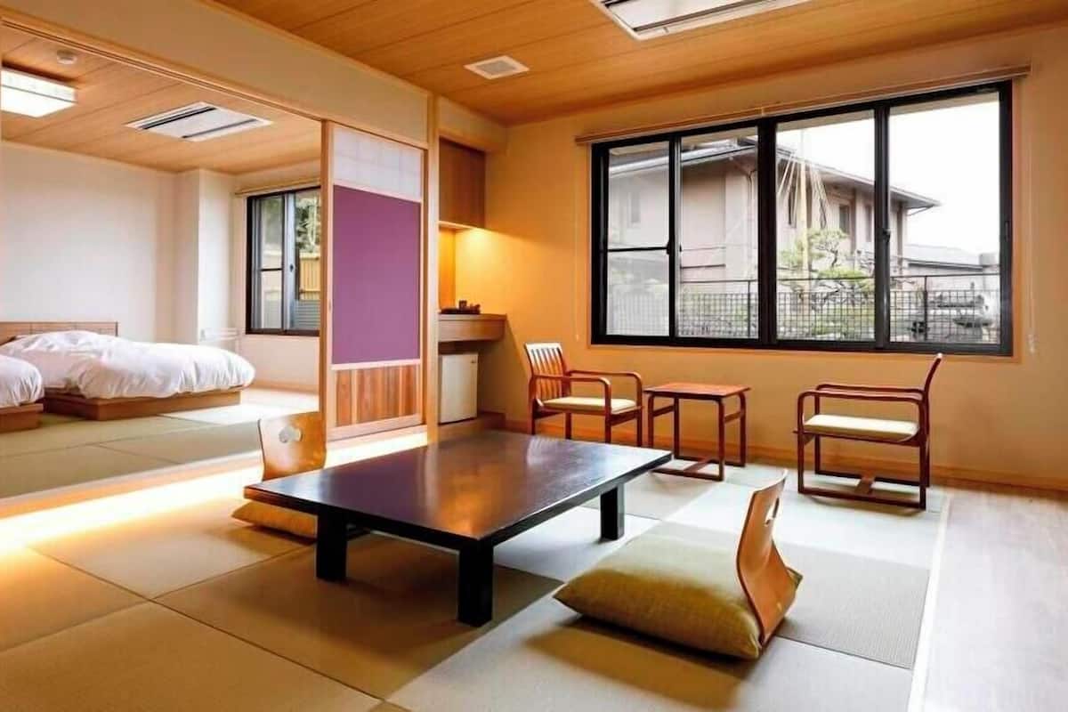 A traditional Japanese-style room with tatami flooring, a low table, and a bed with a futon.