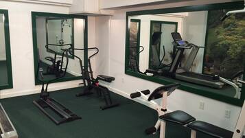 A gym with exercise equipment, mirrors, and a treadmill.