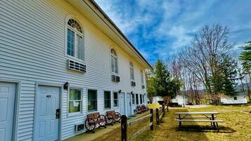 A white building with a porch, numbered 407, and a picnic table in the yard.