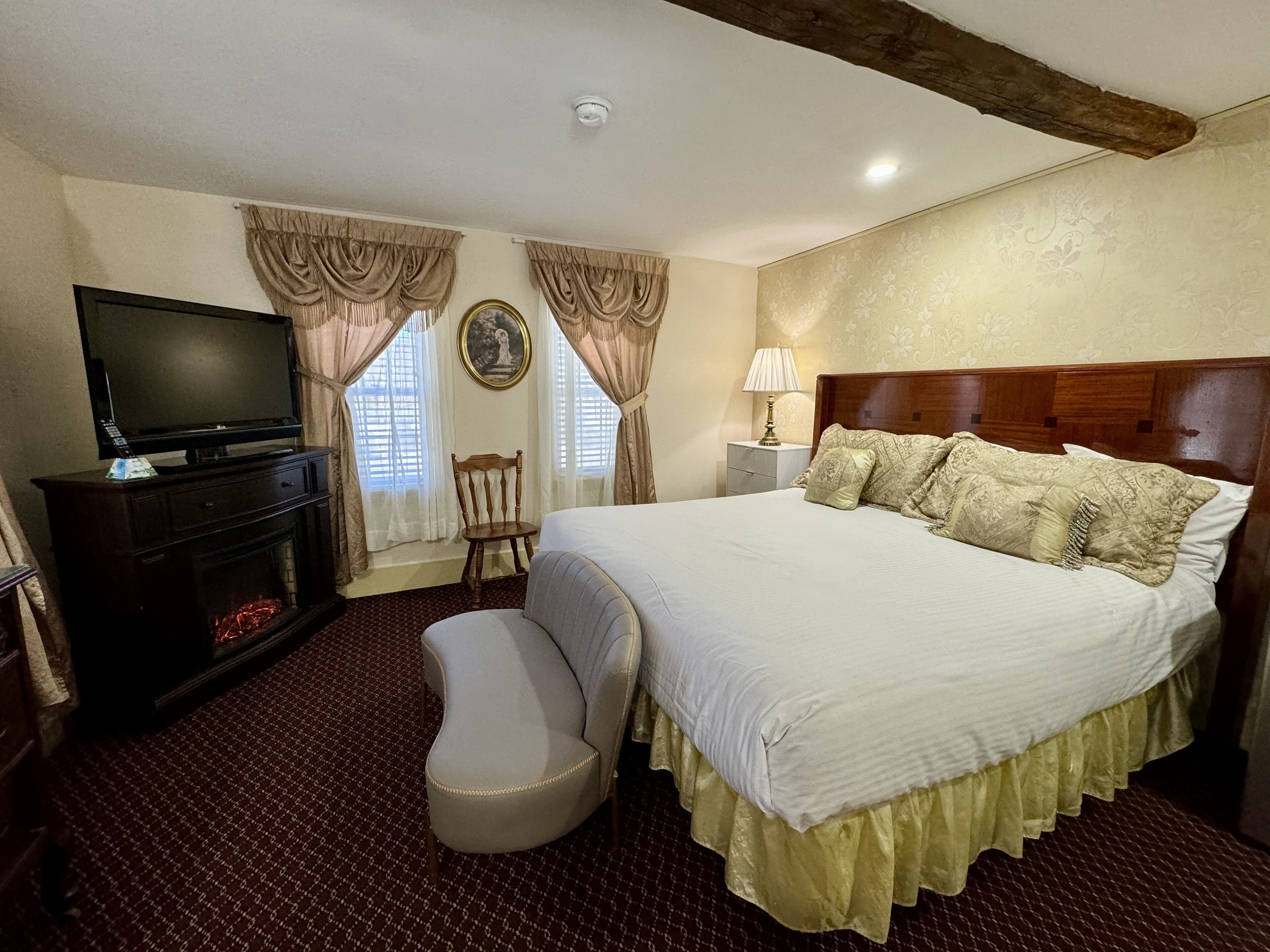 Een hotelkamer met een groot bed, een televisie op een dressoir, een stoel en een lamp.