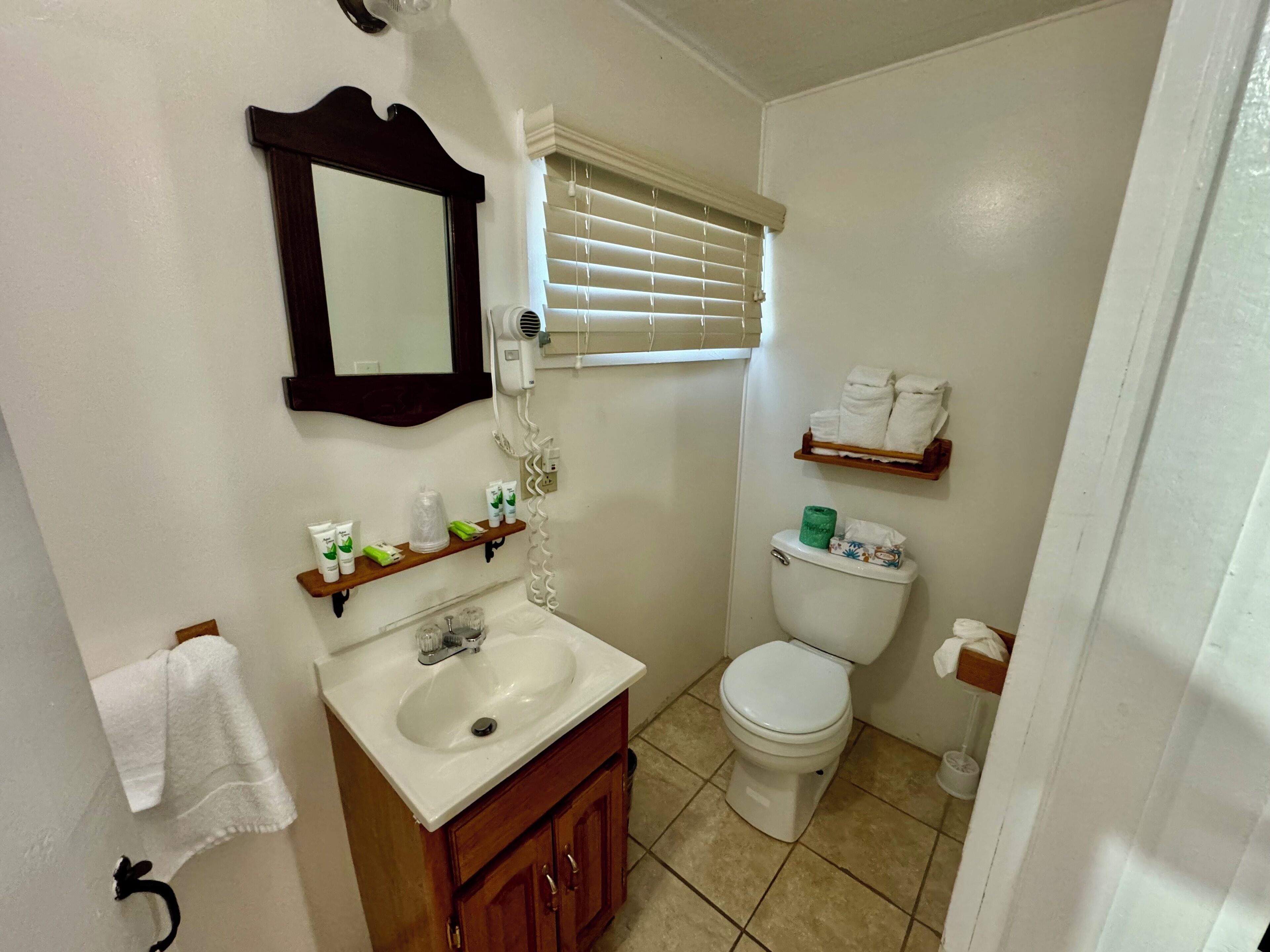 A bathroom with a sink, mirror, toilet, and a towel rack.