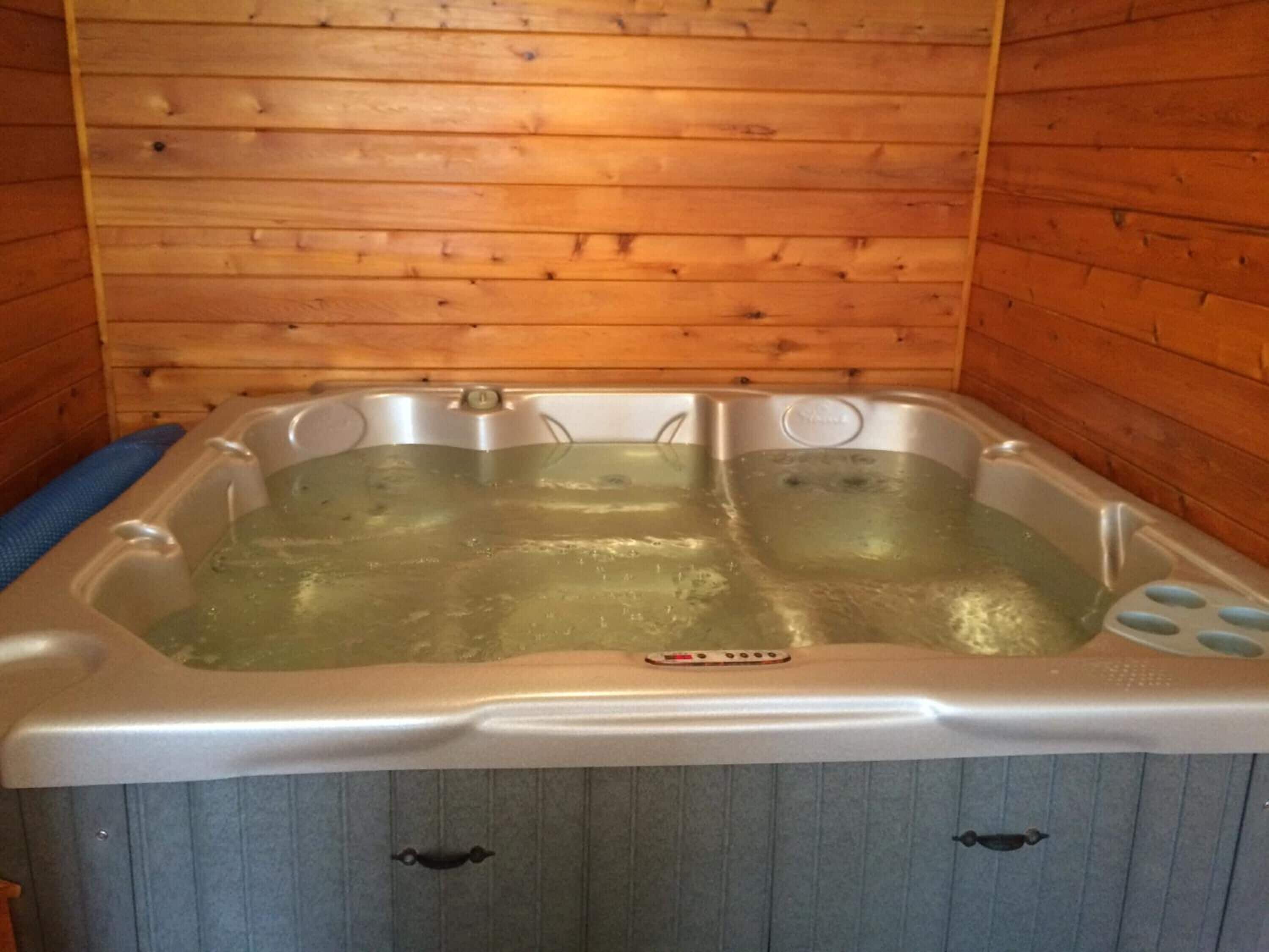 A hot tub with a control panel, set against a wooden wall.
