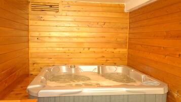 A wooden cabin with a hot tub in the center.