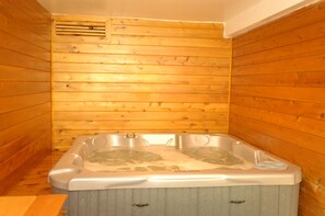 A wooden cabin with a hot tub in the center.