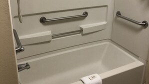 A bathtub with a grab bar, a towel, and a showerhead. - Key West Inn - Lafayette (LaFayette)
