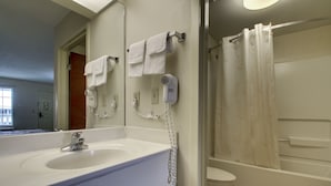 A bathroom with a sink, mirror, two hair dryers, and a shower curtain. - Key West Inn - Lafayette (LaFayette)