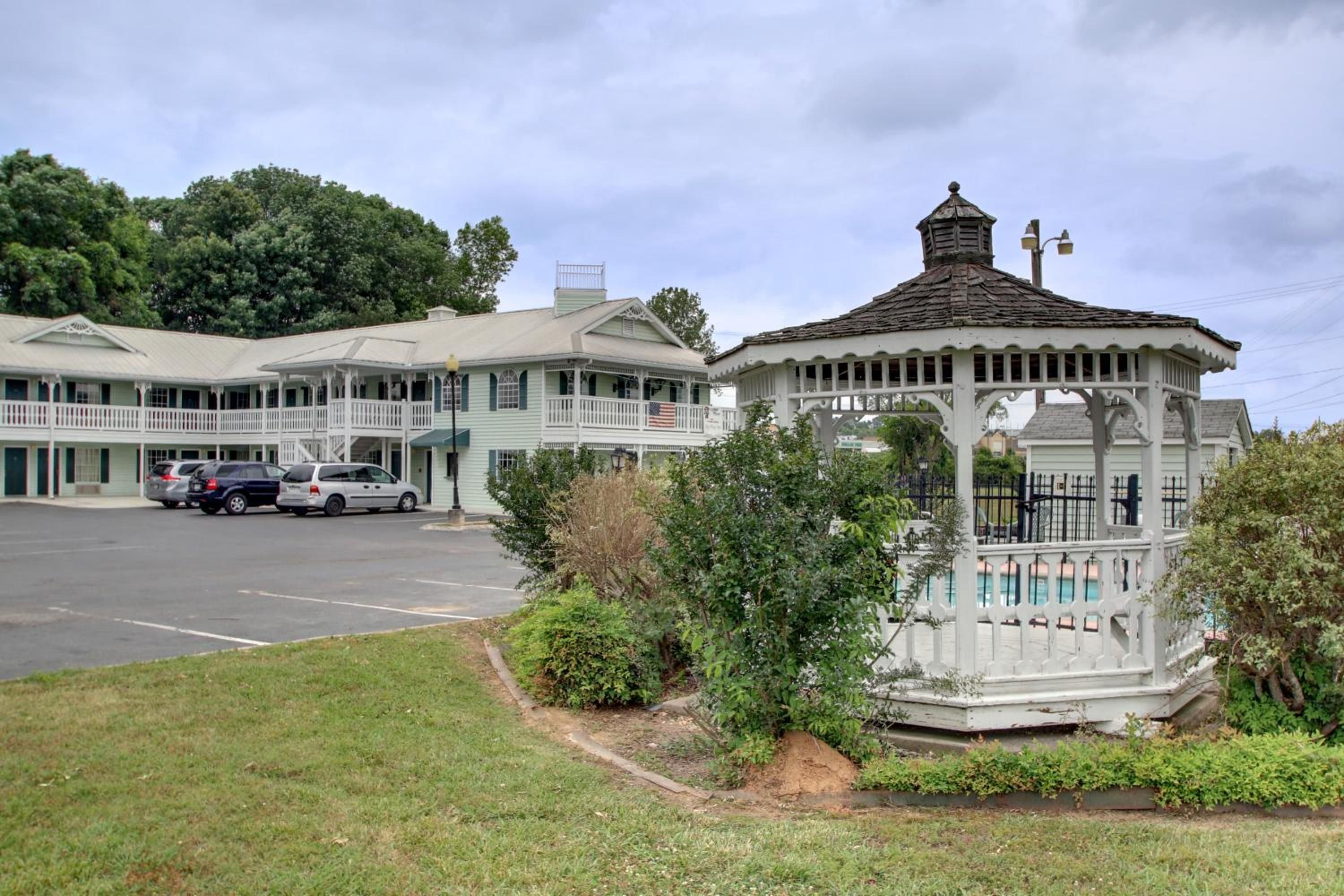 A motel with a gazebo, a parking lot, and a building with a porch.