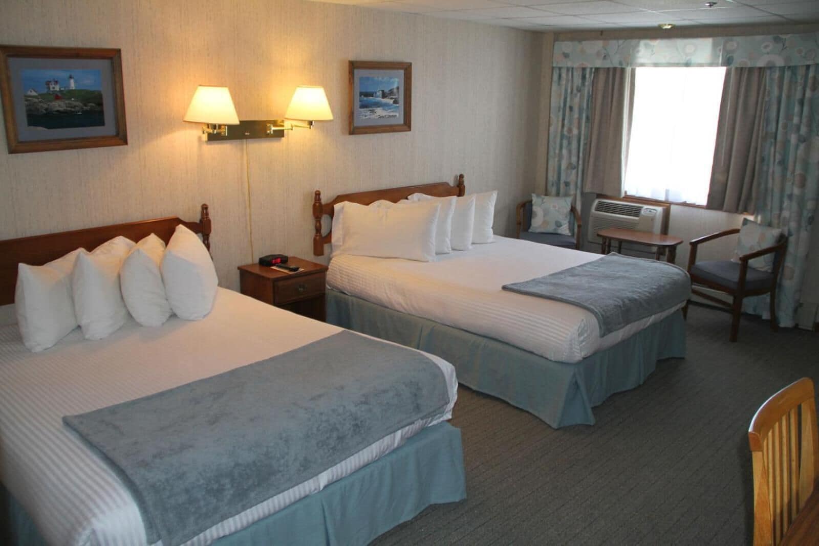 Ein Hotelzimmer mit zwei Betten, einem Schreibtisch und einer Klimaanlage.