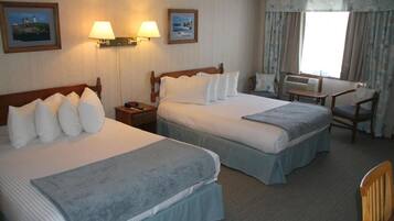 Ein Hotelzimmer mit zwei Betten, einem Schreibtisch und einer Klimaanlage.