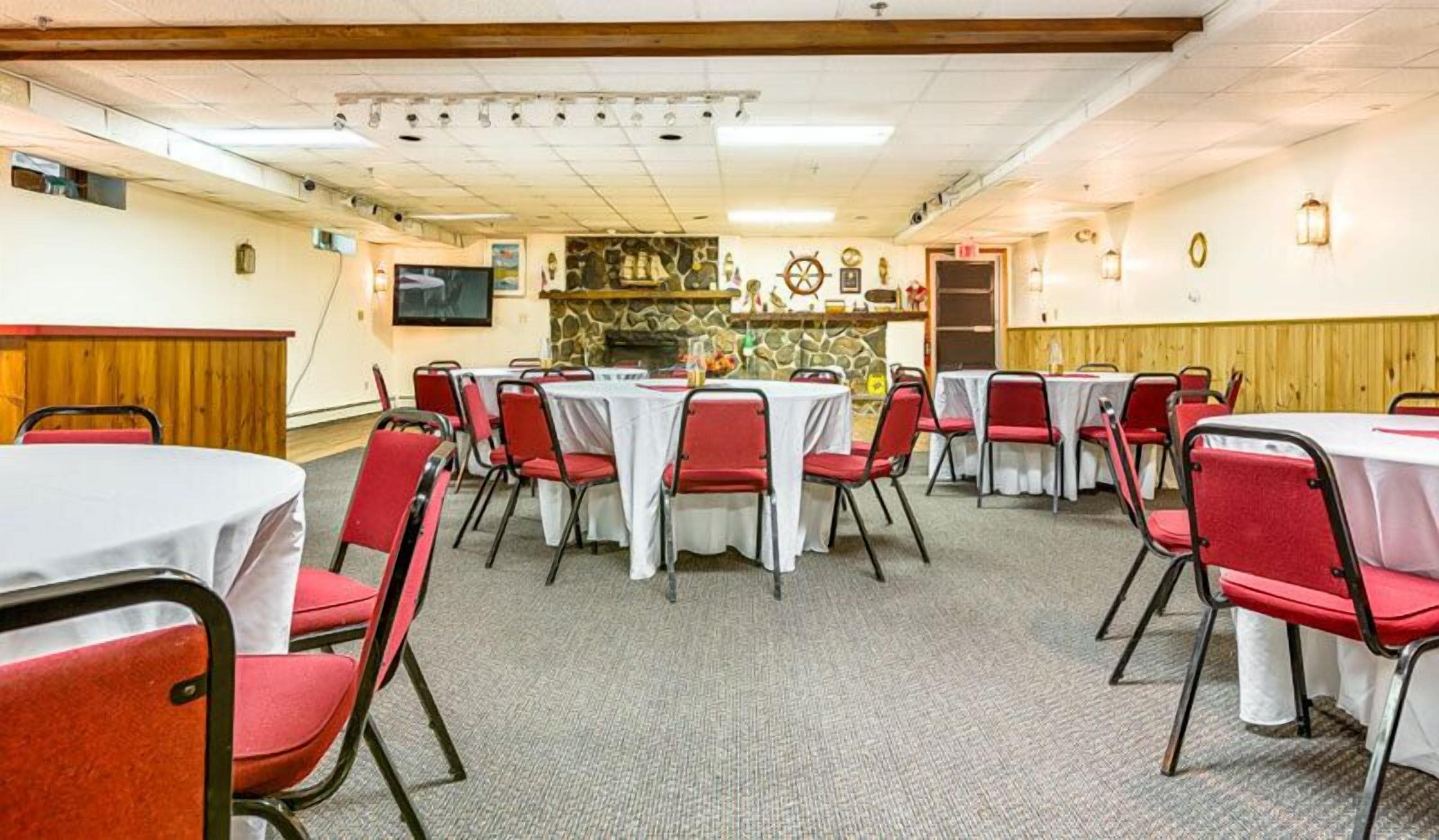 A conference room with multiple tables and chairs, a stone wall with nautical decorations, and a wooden ceiling.