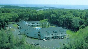 A large, two-story building with a swimming pool, surrounded by dense forest and a parking lot. - The Rhumb Line Resort (Kennebunkport)