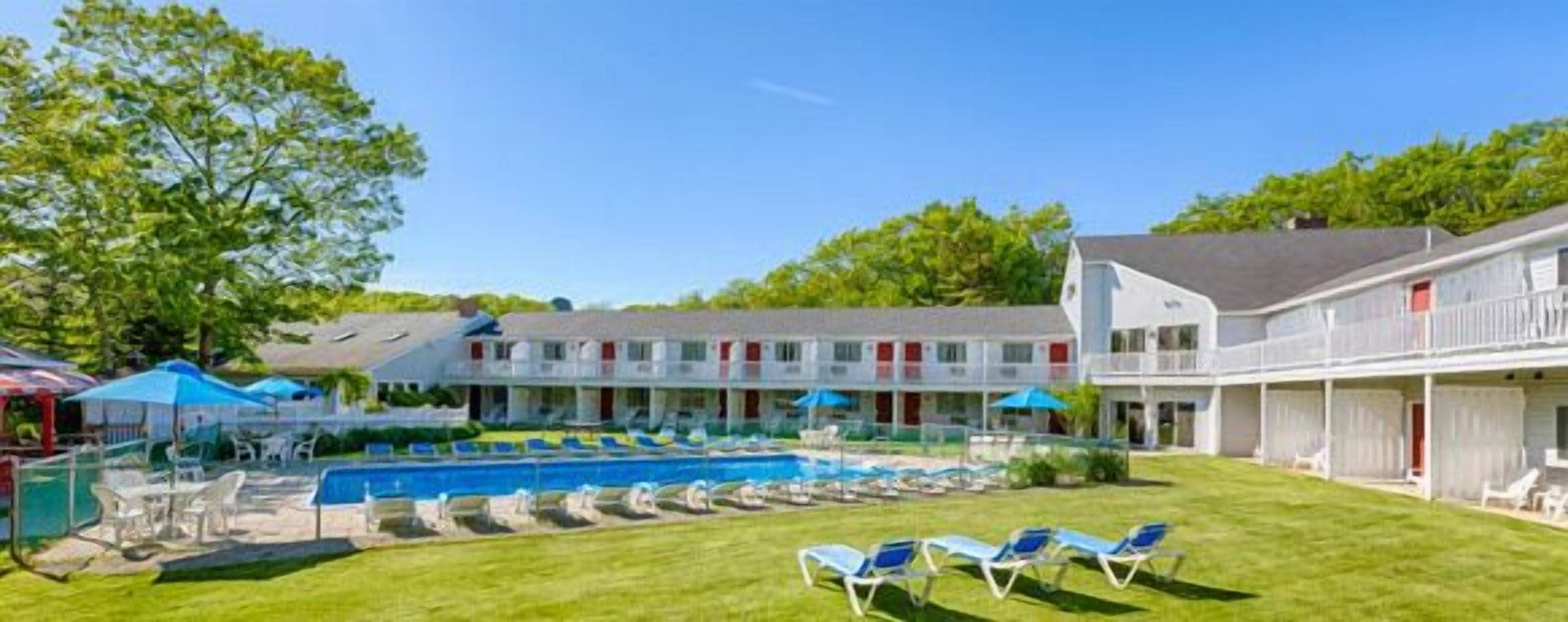 Un hôtel doté d’une piscine, de plusieurs balcons et d’une pelouse bien entretenue.