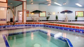 Une piscine intérieure avec un bord carrelé, un espace détente avec des chaises et une petite table.