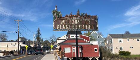Un letrero de bienvenida a Kennebunkport con un muelle de madera que se adentra en el agua.