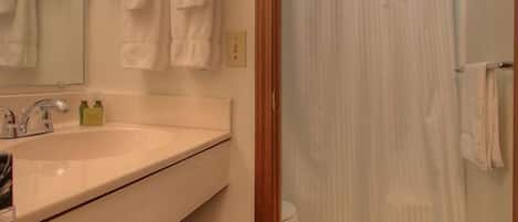 A bathroom with a sink, mirror, and shower curtain.