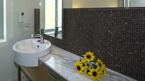 Un baño con lavamanos blanco, un espejo y una pared con mosaicos negros.