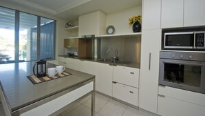 Una cocina moderna con gabinetes blancos, electrodomésticos de acero inoxidable y un ventanal grande.