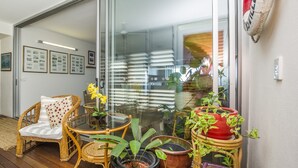 A cozy living area with wicker furniture, a glass table, and various potted plants. - 1 Bright Point Apartment 5404 (Nelly Bay)