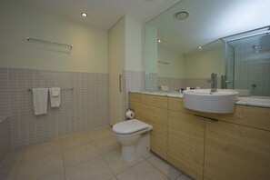 Un baño moderno con inodoro, lavamanos y espejo.