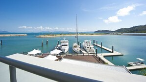 A marina with several boats docked, a clear sky, and a distant view of a hilly landscape. - Blue On Blue Superior Studio Room 1361 (Nelly Bay)