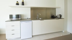 A modern kitchen with a built-in dishwasher, a microwave, a sink, and a kettle. - Blue On Blue Superior Studio Room 1361 (Nelly Bay)