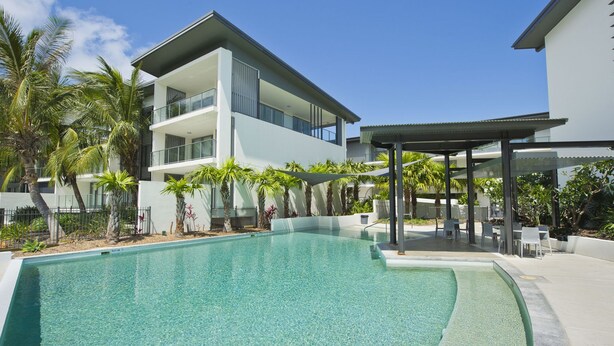 A modern pool area with clear water, surrounded by palm trees and a covered seating area. - Blue On Blue Superior Studio Room 1361 (Nelly Bay)