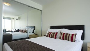 Een hotelkamer met een groot bed, een nachtkastje, een spiegel en een raam.