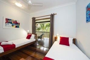 A room with two single beds, a ceiling fan, a painting, and a view of greenery outside. - Marramaninjie (Arcadia)