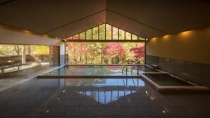 An indoor swimming pool with a view of autumn foliage through large windows. - Hanamaki Onsen Kashoen (Hanamaki)