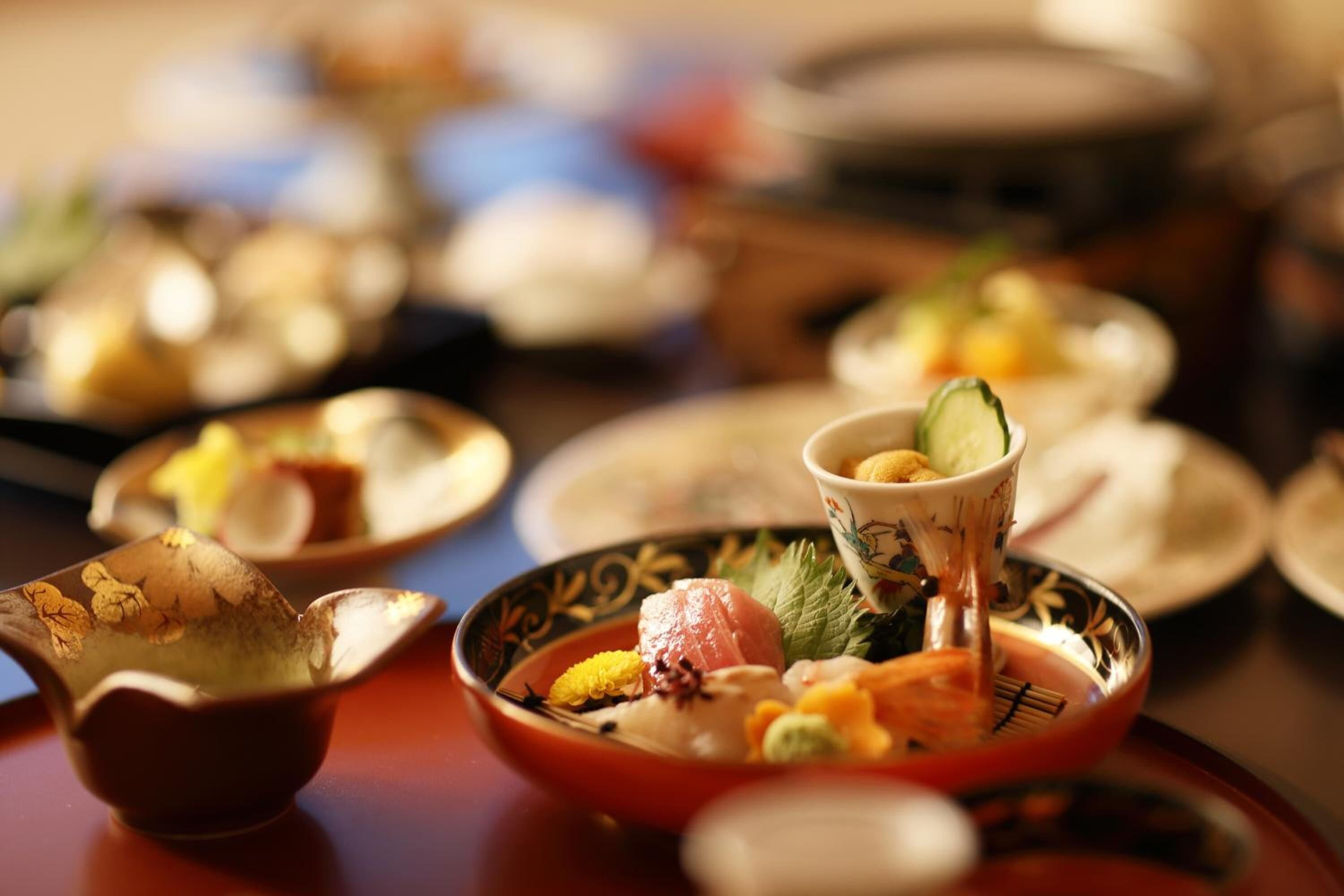 Una mesa con varios platos, incluyendo sushi y otras especialidades asiáticas, indicando un ambiente de comedor.