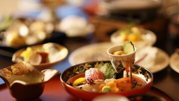 Una mesa con varios platos, incluyendo sushi y otras especialidades asiáticas, indicando un ambiente de comedor.