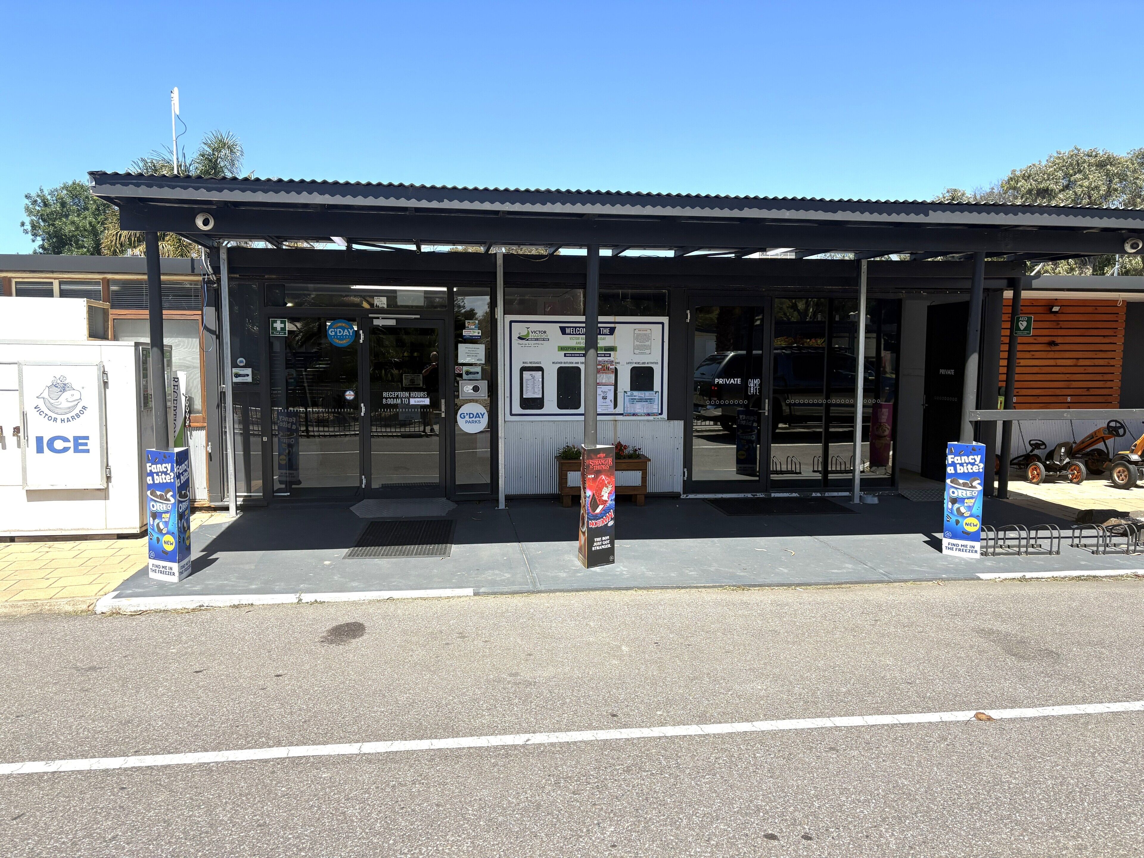 A building with a covered entrance, a sign for Victor Harbor Ice, and a parking area with a tractor.