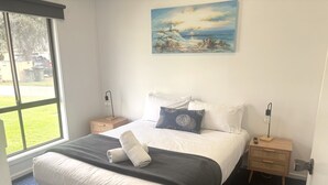 Une chambre à coucher avec un grand lit, une table de chevet avec une lampe et un tableau au mur.