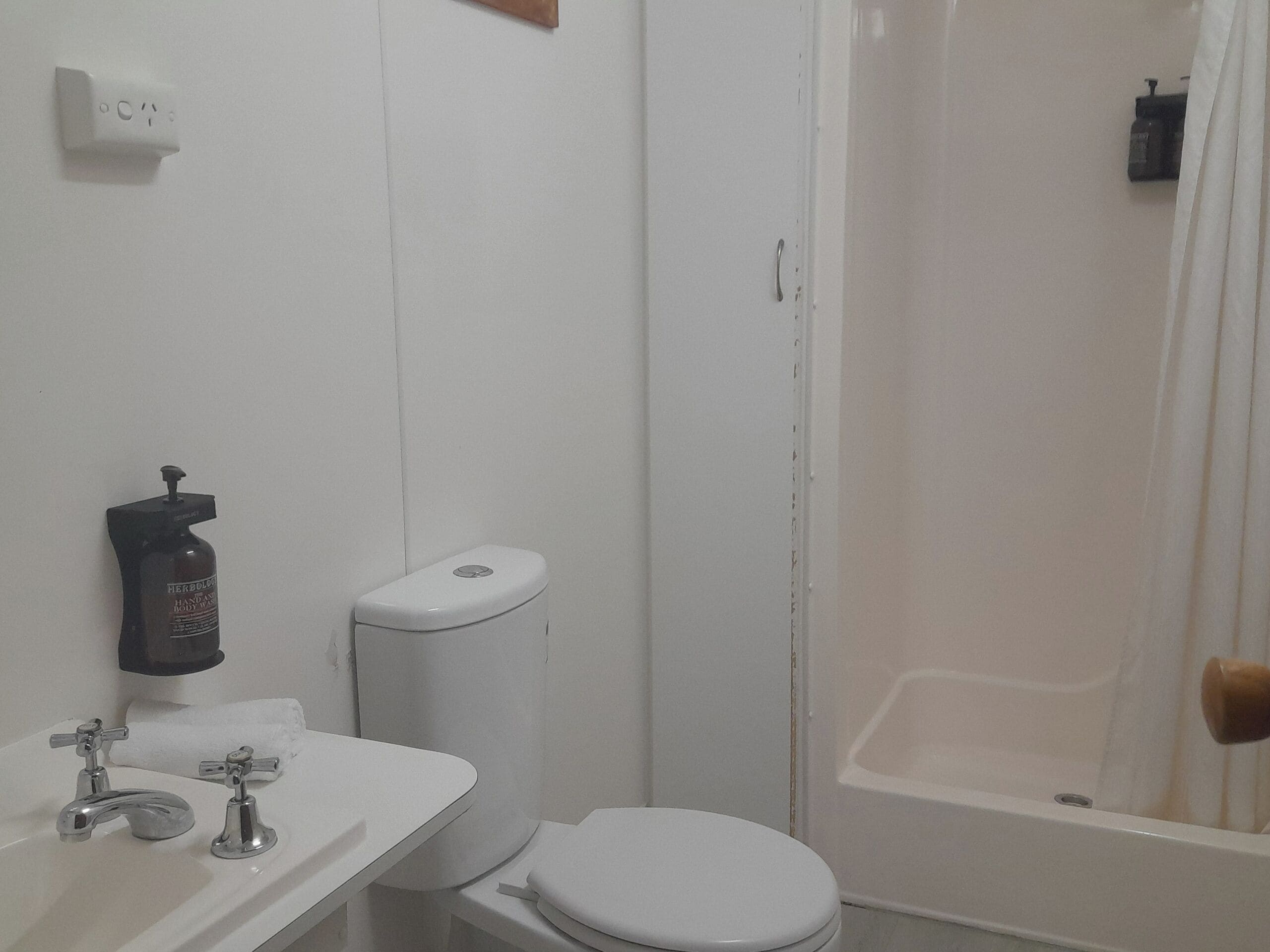 A small bathroom with a toilet, sink, and shower.