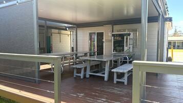 An outdoor patio area with picnic tables and benches, a vending machine, and a covered seating area.