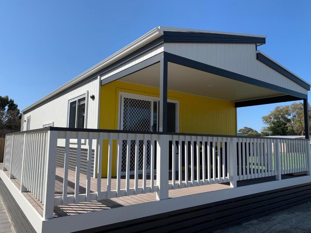 A single-story building with a covered porch and a white railing.