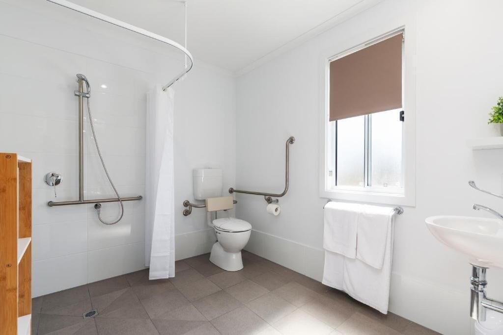 A modern bathroom with a shower, toilet, and sink.