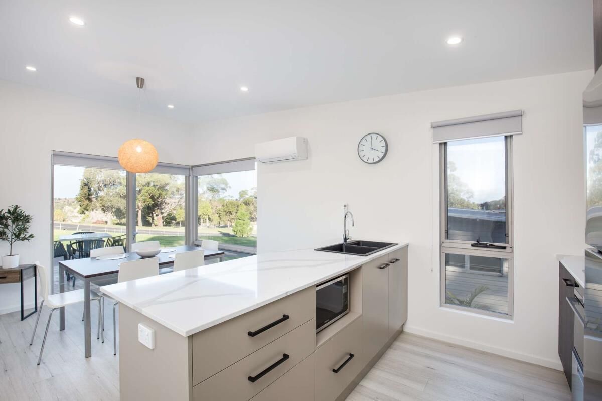 A modern kitchen with a large island, built-in oven, and a window with a view of the outdoors.
