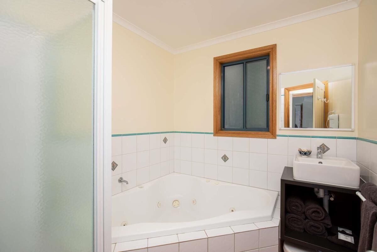 Een badkamer met een wit bad, een wastafel en een spiegel.