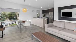 Un salon moderne comprenant un canapé, une table basse et un coin repas avec des chaises et une table.