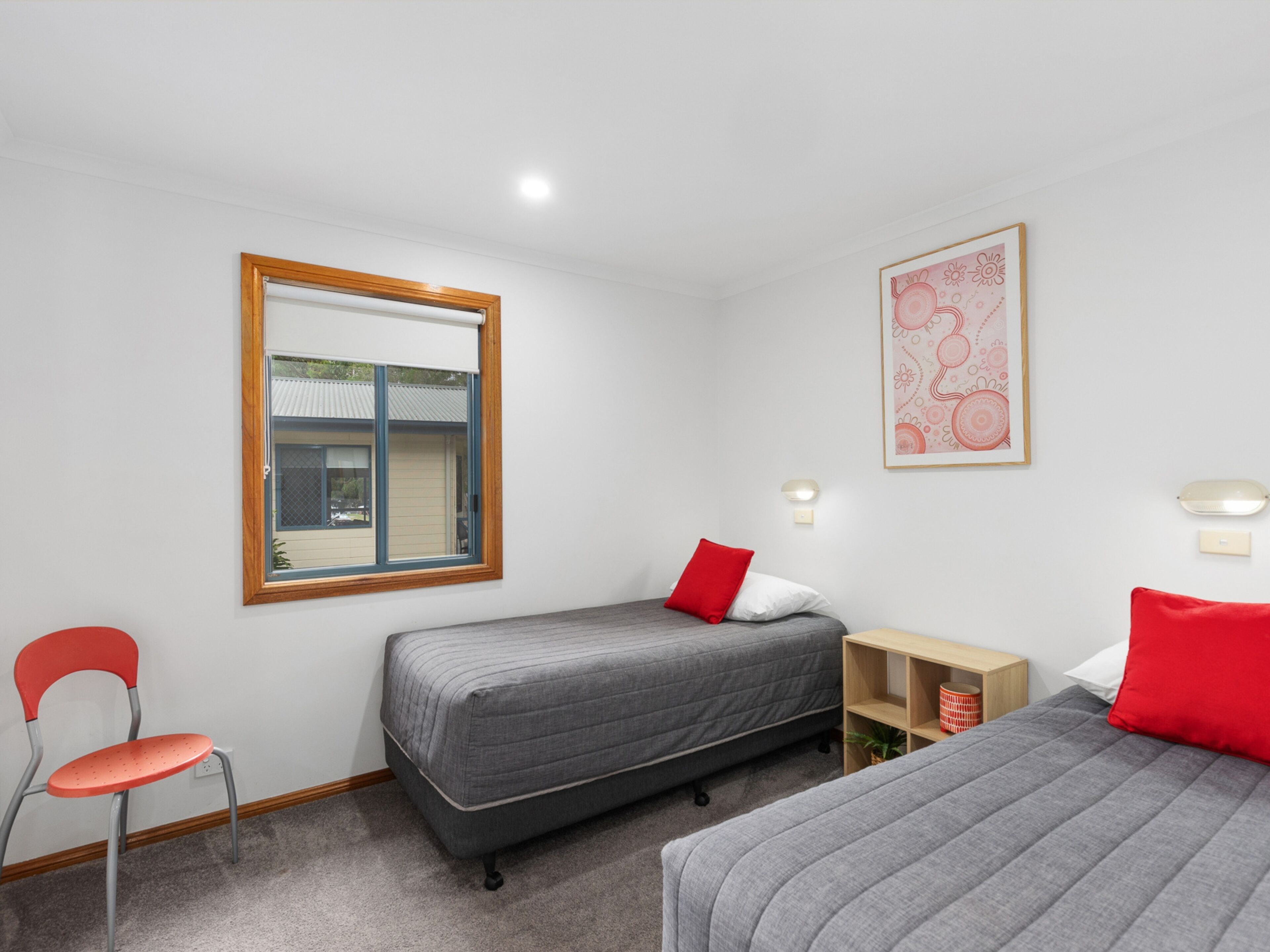 A room with two beds, a chair, a small table, and a window.