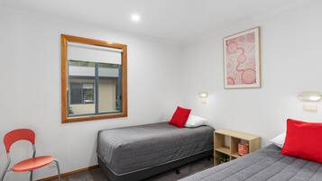 A room with two beds, a chair, a small table, and a window.