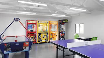 A room with a ping pong table, arcade games, and a table tennis table.