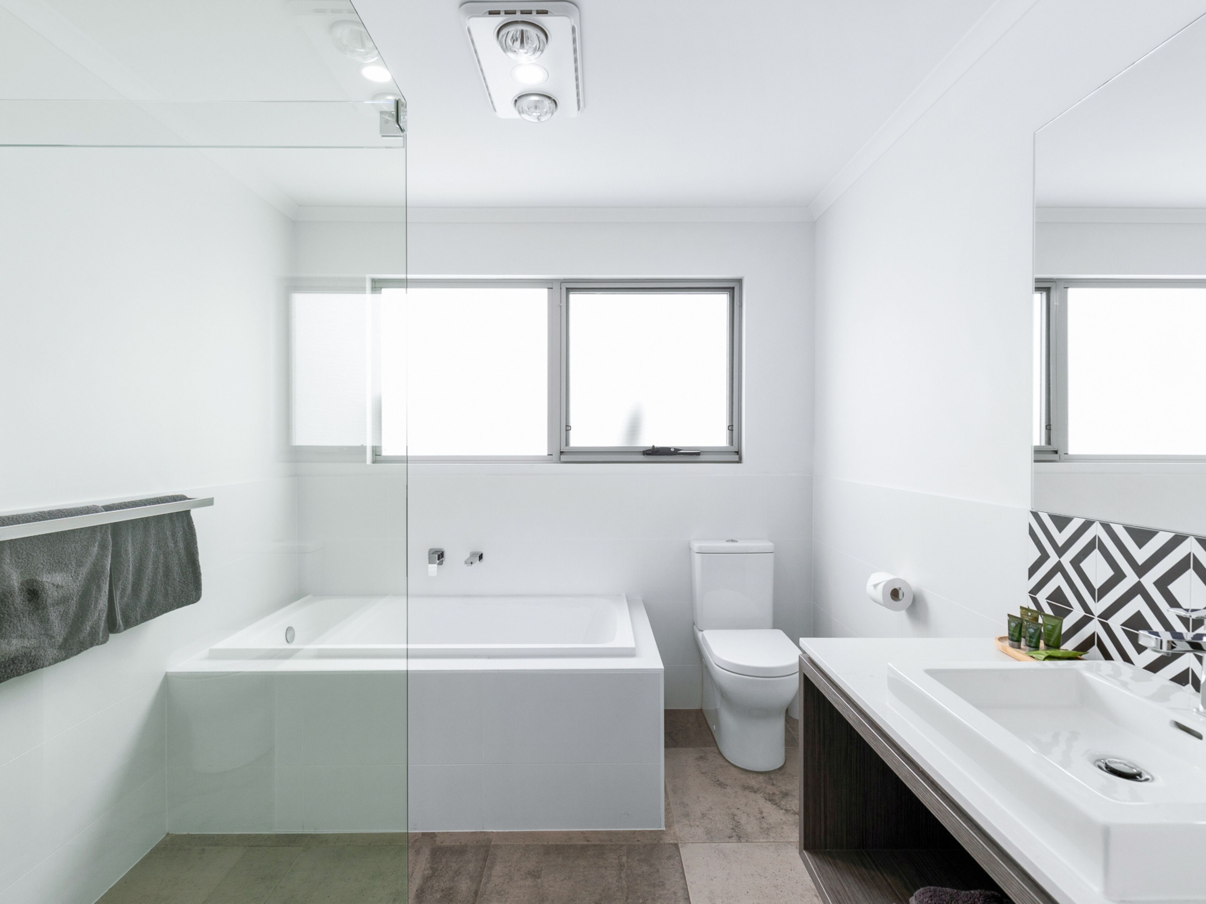 A modern bathroom with a glass shower enclosure, a freestanding bathtub, a toilet, and a vanity with a sink.