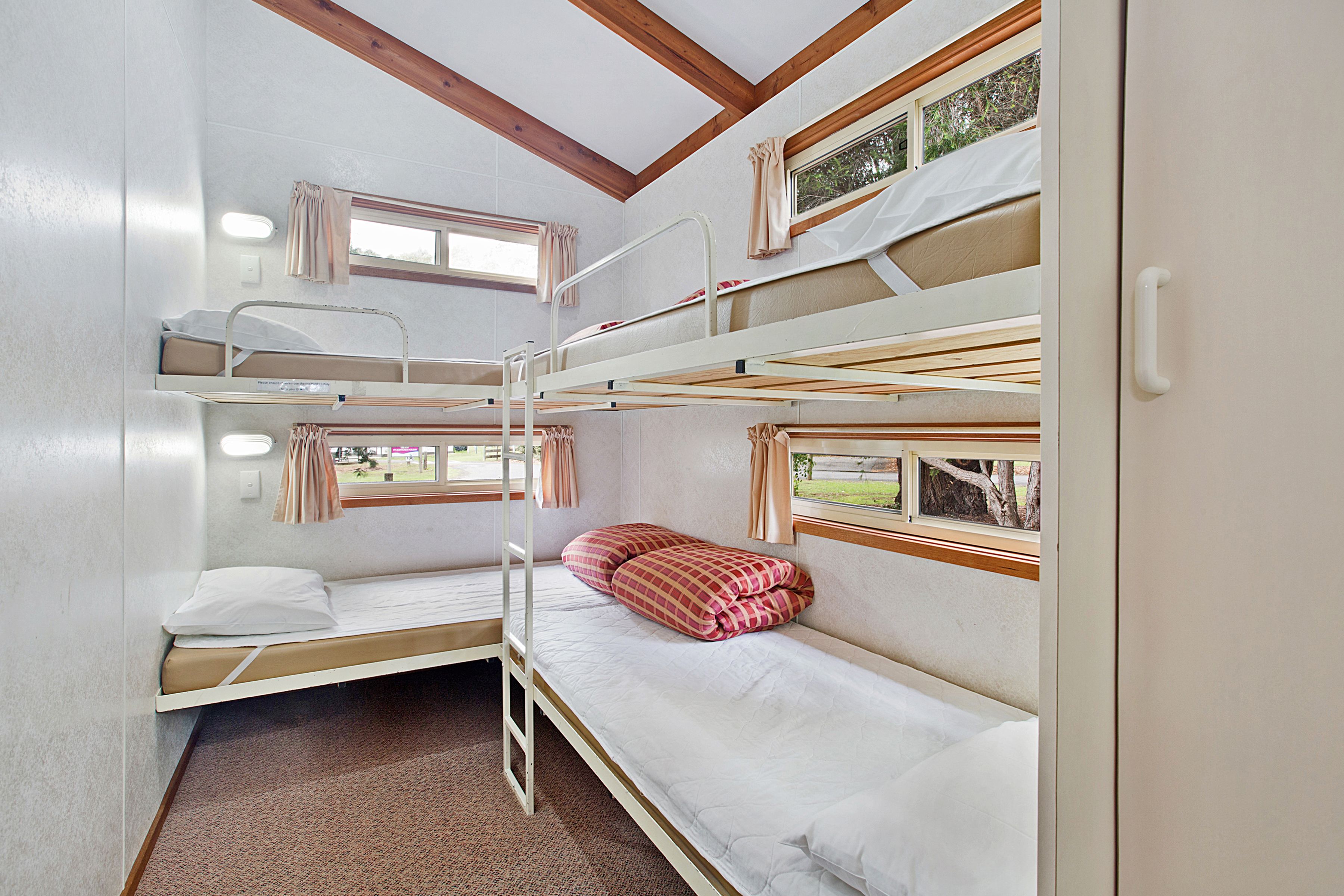 Quarto com beliche, janela e vista para o verde lá fora.