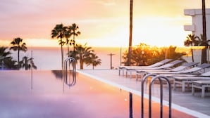 An infinity pool with lounge chairs and palm trees, reflecting a sunset. - HOVIMA Cool Costa Adeje (Adeje)